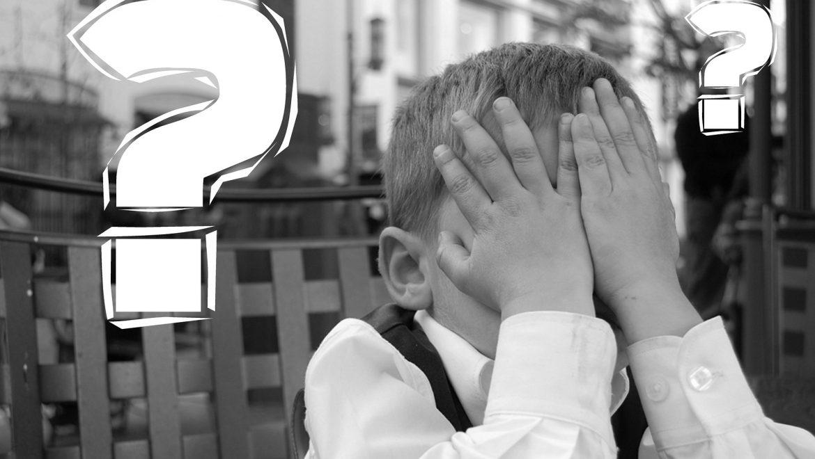Child with hands covering his face and question marks around